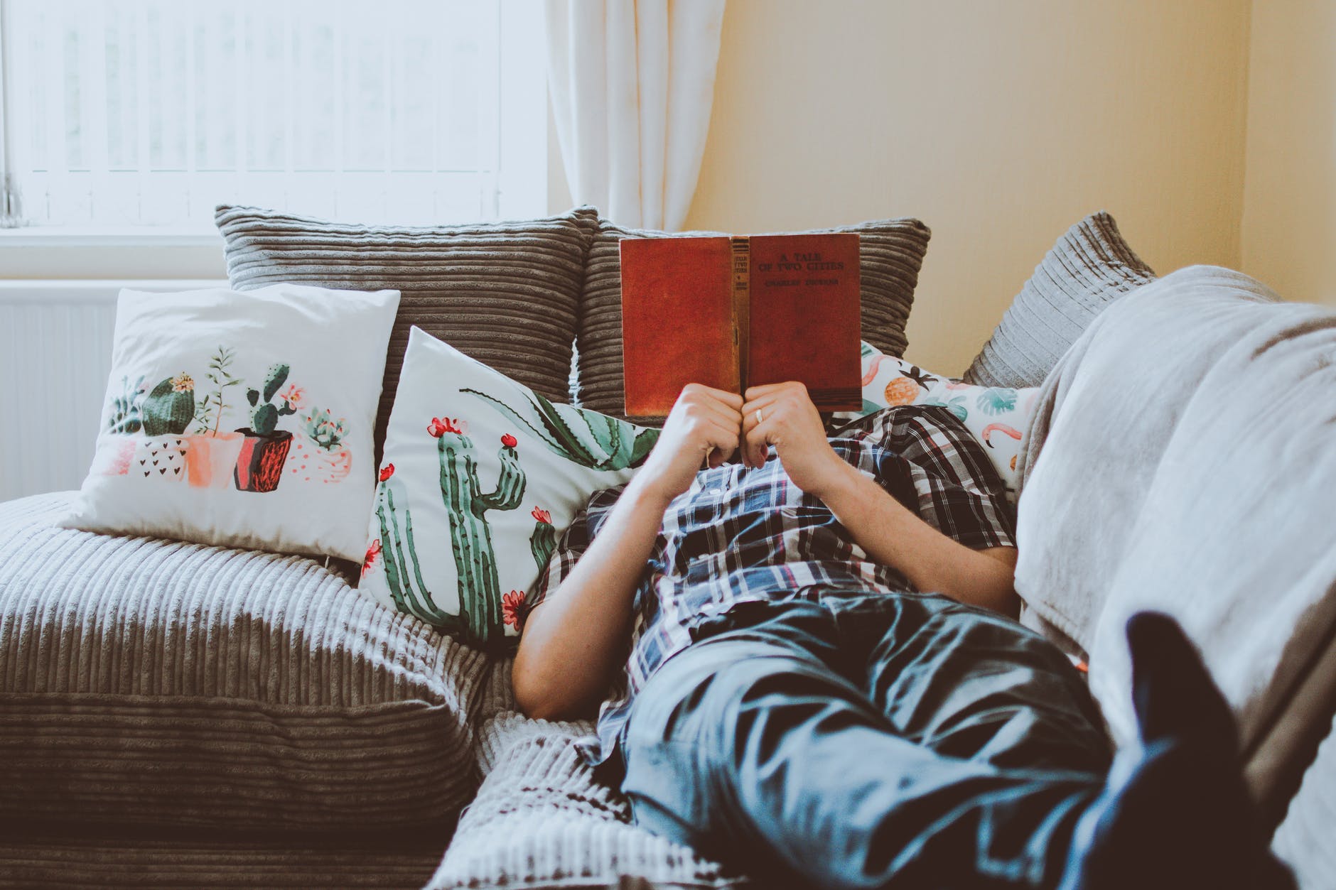 person laying on sofa while reading book