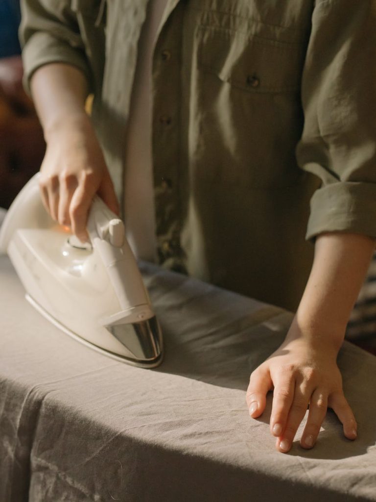 person in brown button up shirt holding white clothes iron