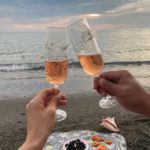 couple clinking glasses of champagne on seashore