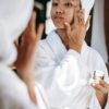 black woman with towel applying cream on face