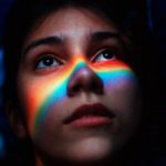 woman with rainbow light reflecting her face