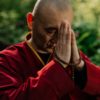 a monk in red robe praying