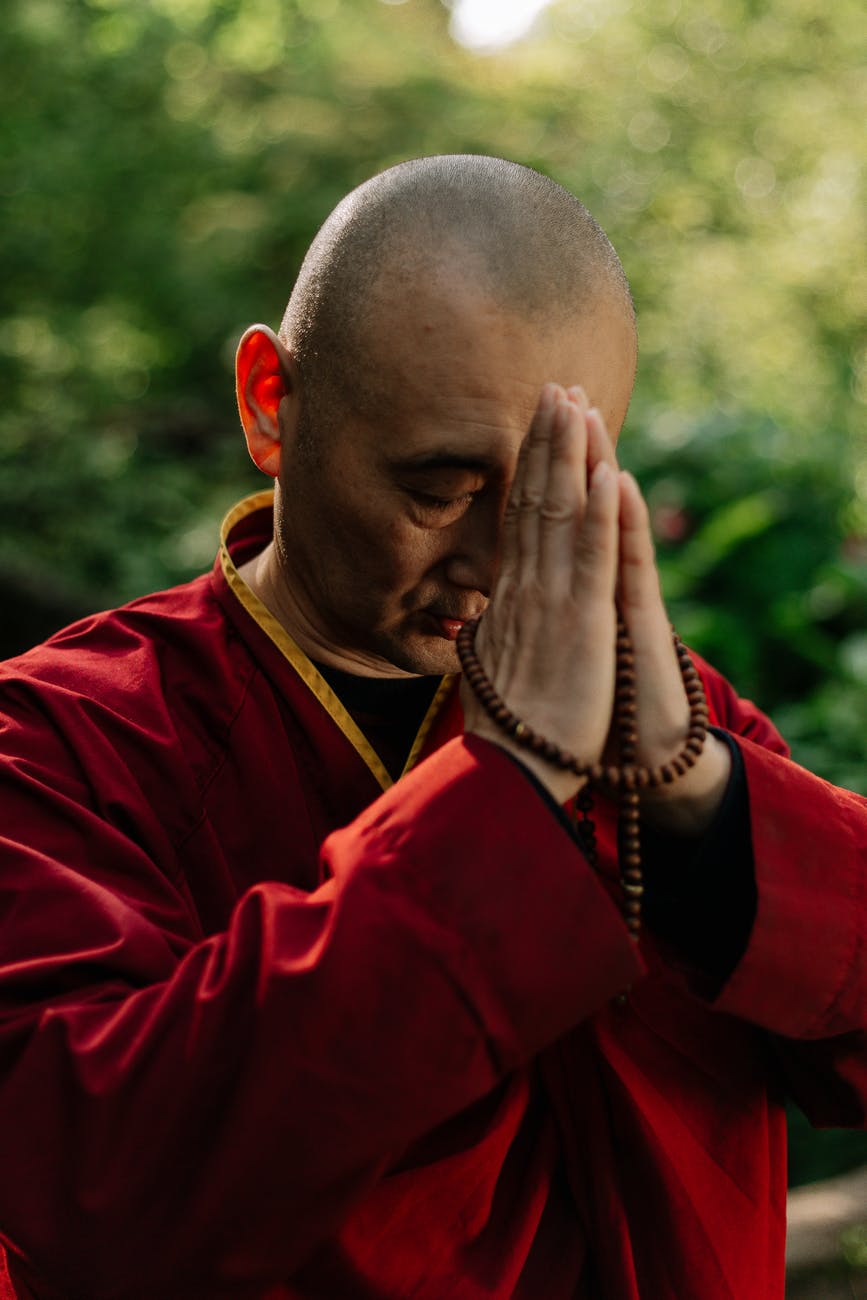 a monk in red robe praying