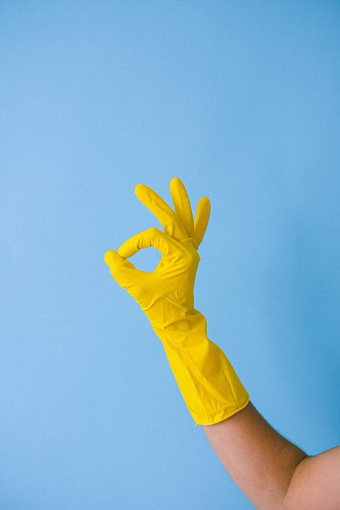 crop faceless person in rubber glove showing okay gesture