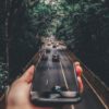 forced perspective photography of cars running on road below smartphone
