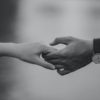 monochrome photo of couple holding hands