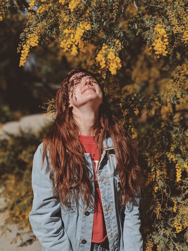 woman standing under yellow leaf tree