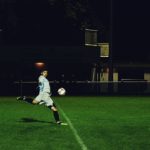 person kicks soccer ball in field