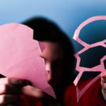 person holding two parts of paper heart