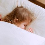 photo of child laying on bed