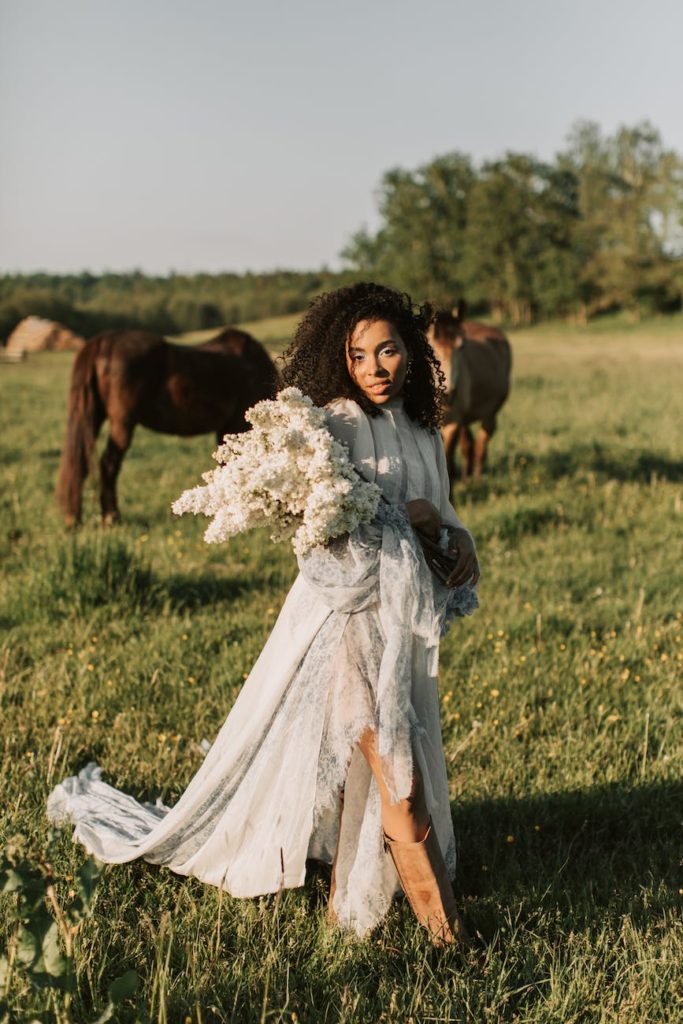 woman in white gown standing near horses