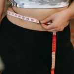 plus size woman using measuring tape on belly