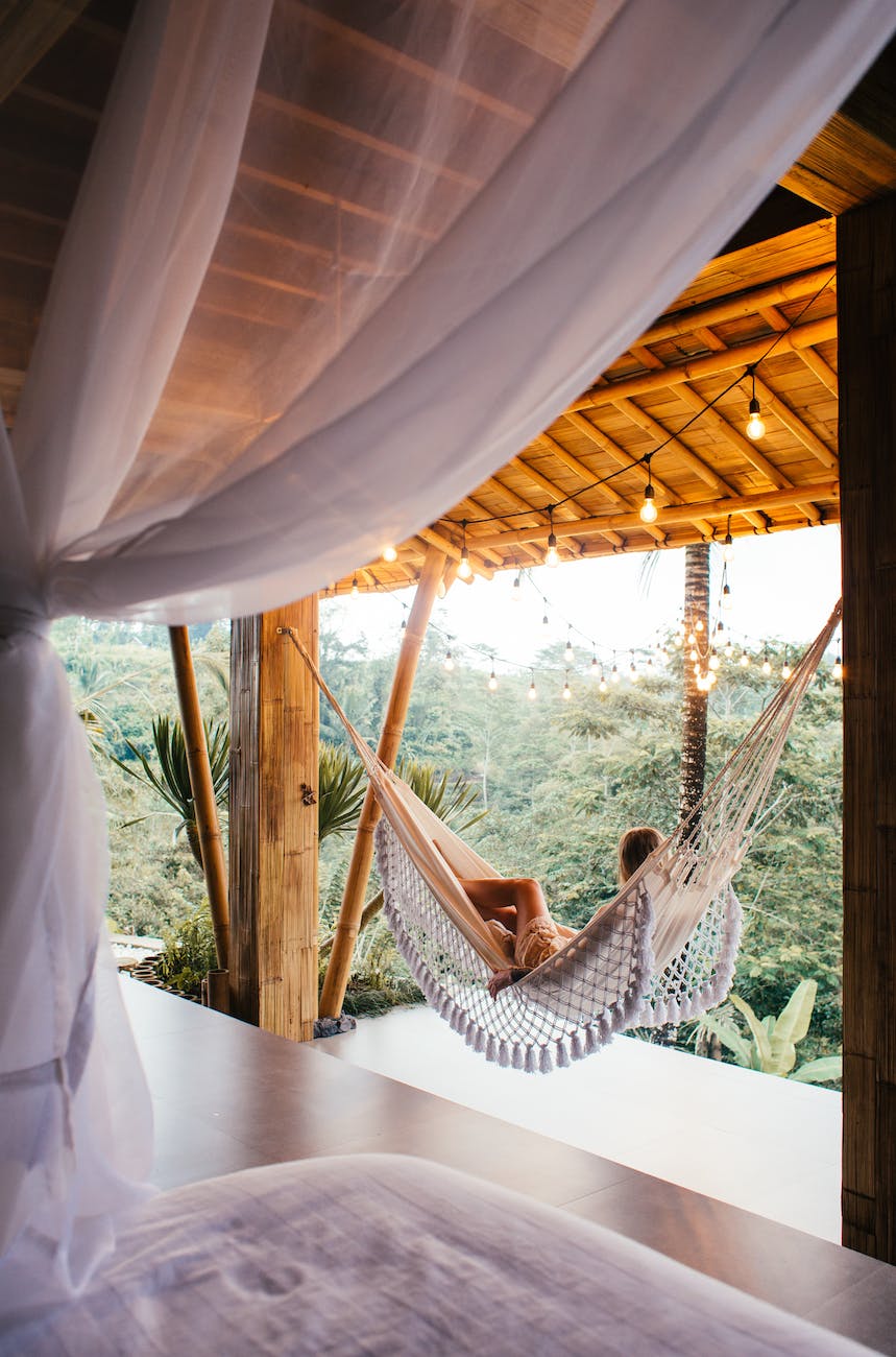 unrecognizable traveler in hammock against bed in tropical resort