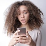 surprised young woman browsing mobile phone