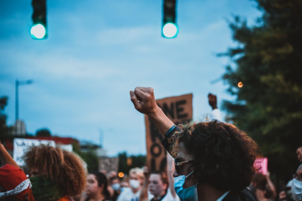 unrecognizable man with fist up during demonstration in evening