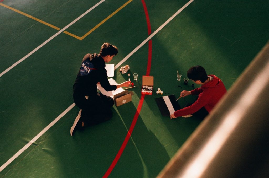 anonymous men painting marking lines on sports court