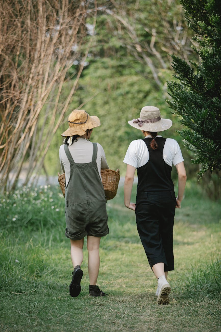 faceless gardeners strolling on path near grass in nature