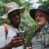 multiracial friends sharing smartphone in summer forest