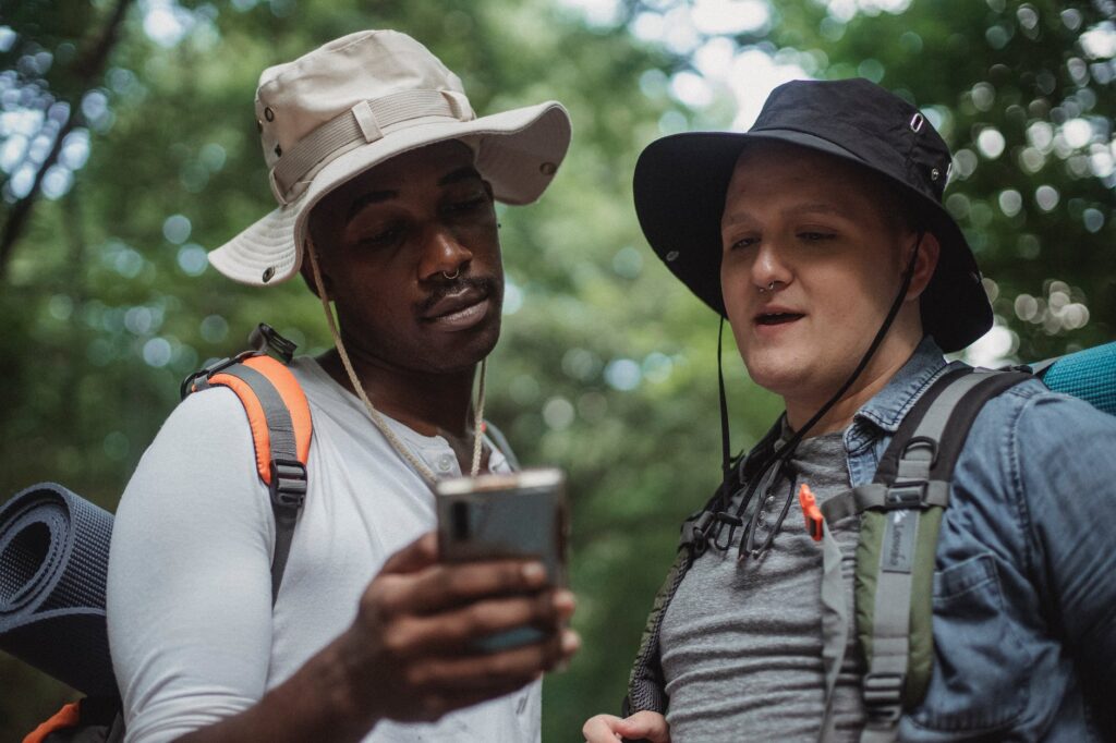 multiracial friends sharing smartphone in summer forest