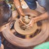 person making clay pot in front of girl during daytime