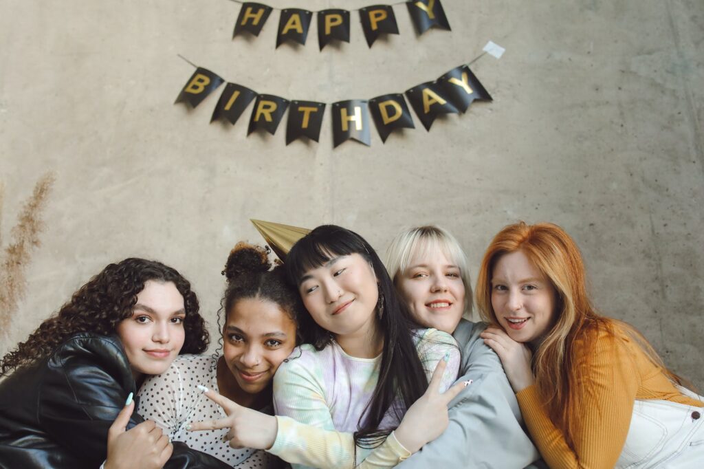 women at birthday party posing for a photo with happy birthday written above