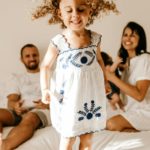 happy little kid having fun on bed with cheerful parents