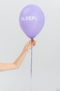 a hand holding a purple balloon
