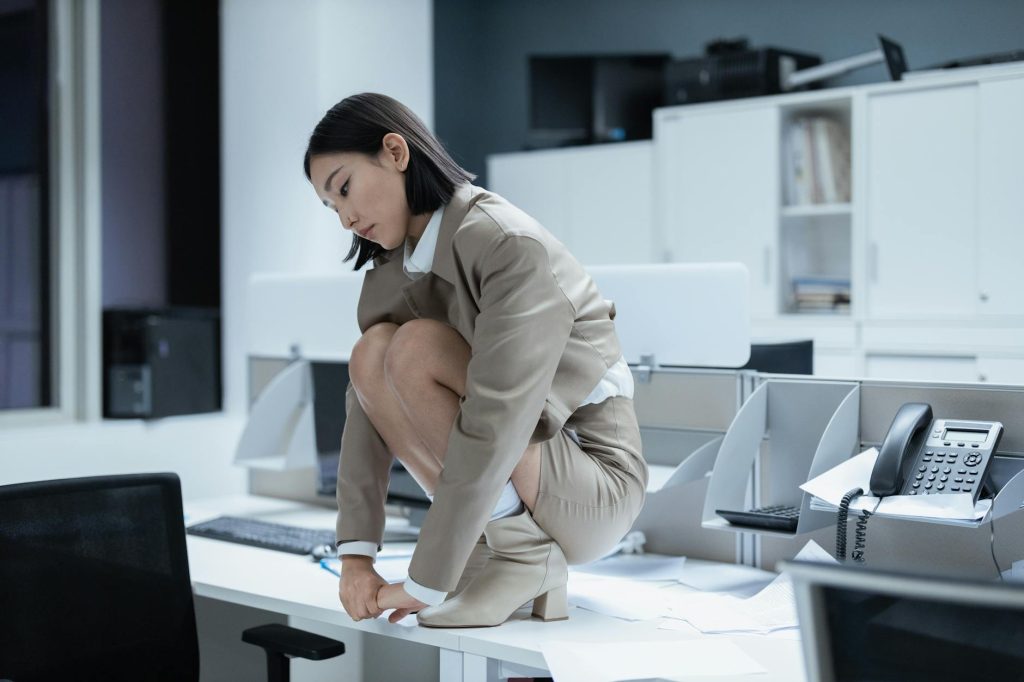 overworked employee crouching on desk in office